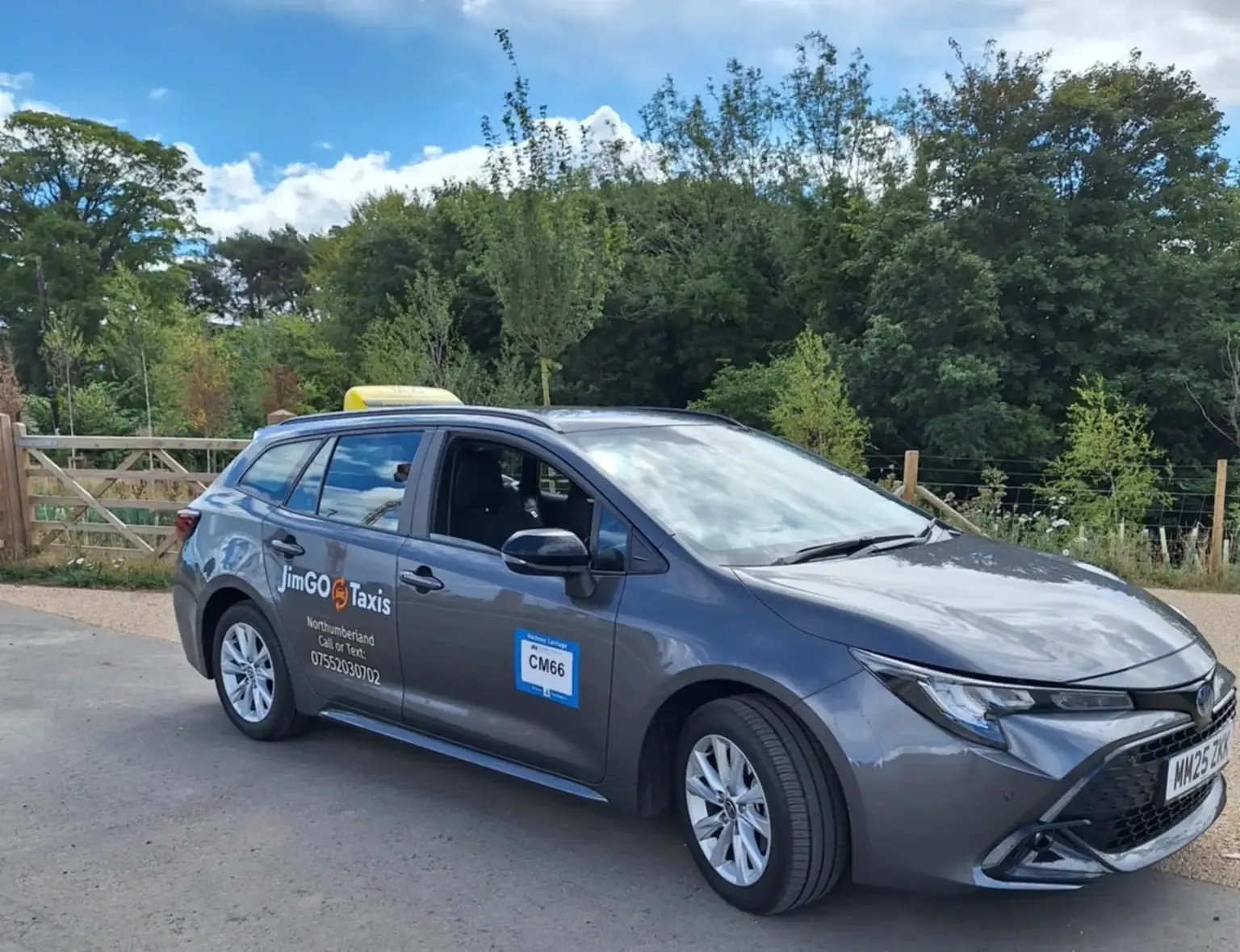 The grey JimGO Taxis Toyota Corolla Hybrid with its yellow roof sign